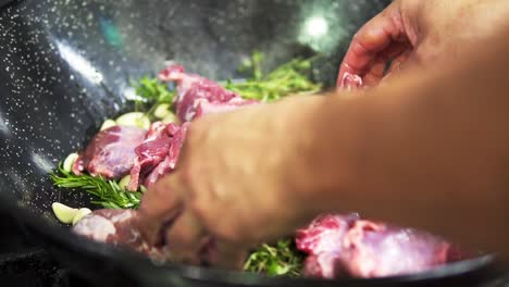 Hands-leaving-in-the-hot-pan-pieces-of-meat-to-cook-with-rosemary-in-slow-motion