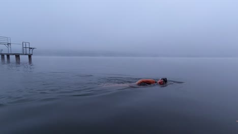 Woman-open-water-swimming-in-winter-in-a-foggy-lake