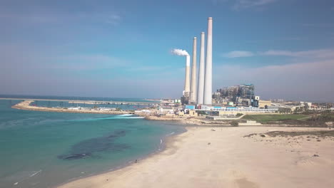 Wide-Aerial-dolly-shot-of-the-Hadera-Desalination-Plant,-Israel,-over-the-beach-and-water
