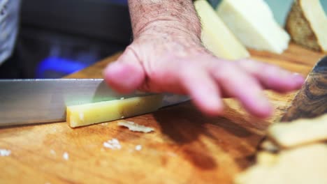 Shot-of-a-person-cutting-cheese-with-a-knife-on-a-wooden-board-in-slow-motion