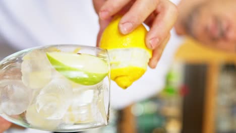 Clip-Vertical-De-Un-Barman-Preparando-Un-Gin-Tonic-Cepillando-El-Limón-Alrededor-Del-Borde-Del-Vaso-Para-Darle-Un-Toque-Cítrico