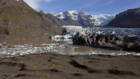 Luftaufnahme:-An-Einem-Sonnigen-Tag-Kommt-Ein-Mann-Vorbei,-Der-Auf-Einem-Hügel-In-Der-Nähe-Des-Svinafellsjökull-Gletschers-Steht
