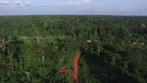 Drone-shot-tracking-a-Jeep-driving-on-a-distant-jungle-route-in-Cameroon,-Africa