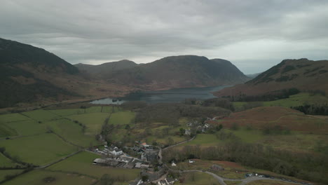 Flying-over-quaint-English-village-towards-lake-and-mountains-at-Buttermere-English-Lake-District-UK