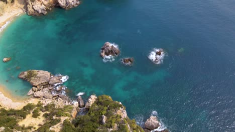 Aerial,-tilt-up-view-of-rocky-cliff-beach-with-no-people-on-Corfu,-Greece,-slow-motion