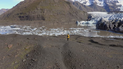 Aerial:-Orbit-shot-of-one-man-standing-on-a-hill-near-Svinafellsjokull-glacier-during-a-sunny-day