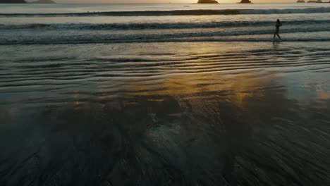 Sonnenuntergangsreflexionen-Am-Meeresufer-Mit-Touristen-Am-Strand-Von-Costa-Rica
