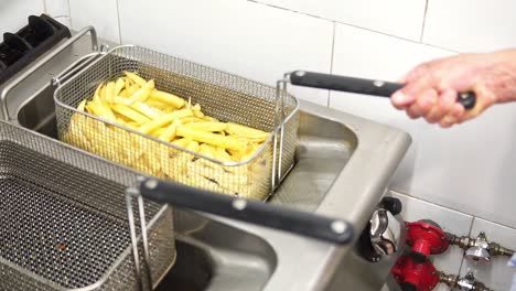 Person-frying-cut-potatoes-in-the-oil-of-a-deep-fryer-in-slow-motion-in-the-kitchen