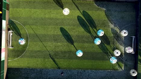 Zorb-football-players-running-around-field-at-sunset-with-bubble-shadows