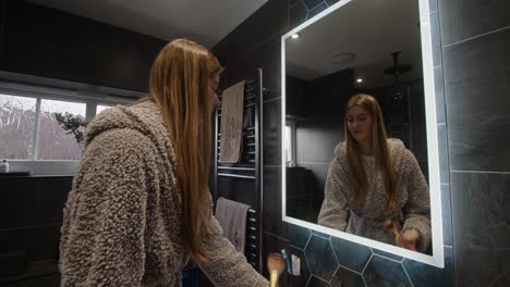 Weibliches-Model-Schaut-In-Einen-Badezimmerspiegel-Mit-Hintergrundbeleuchtung-Und-Schminkt-Sich