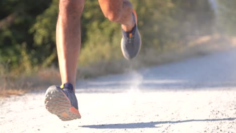 Professional-runner-running-fast-on-dirt-path-in-smooth-slow-motion-tracking-from-front