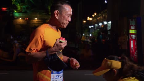 Happy-runner-taking-a-break-for-a-fruit-snack-during-the-Samui-Run,-Koh-Samui-Island,-Malaysia