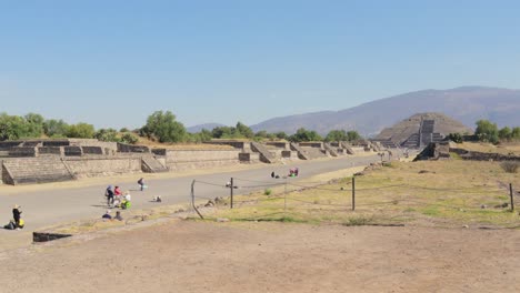 Una-Amplia-Plataforma-Rodante-En-Una-Toma-Del-Sitio-Arqueológico-De-Teotihuacan-En-México,-Con-La-Pirámide-De-La-Luna-Al-Fondo-Y-Algunos-Turistas-Alrededor,-En-Un-Día-Claro-Y-Soleado