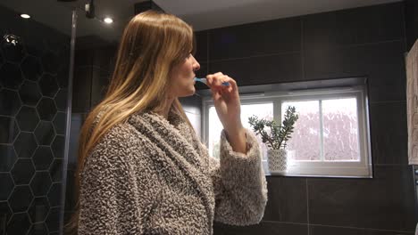 Weibliches-Model-Beim-Zähneputzen-In-Einem-Modernen-Badezimmer-Mit-Bademantel-Und-Morgenmantel