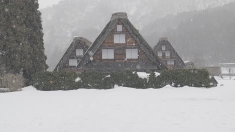Una-Toma-En-Cámara-Lenta-De-Tres-Casas-Bajo-La-Nieve-En-El-Pequeño-Pueblo-De-Shirakawago-Durante-El-Invierno-En-Japón
