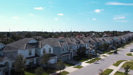 Aerial-view-rising-behind-palm-trees-revealing-houses-in-a-neighborhood-of-Orlando,-sunny-day-in-Florida,-USA