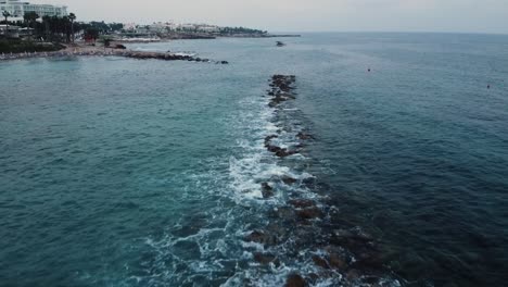 Aerial-drone-shot-of-waves-crashing-over-rocks-in-the-sea---Paphos,-Cyprus