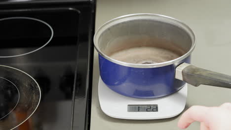 Using-a-digital-scale-to-zero-out-a-sauce-pan-so-precise-measurements-can-be-made
