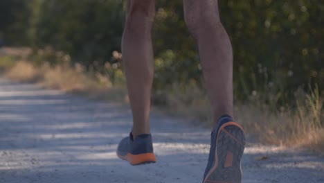 Professional-runner-running-fast-on-dirt-path-in-smooth-slow-motion-tracking-shot