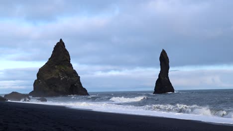 Hermosas-Rocas-En-El-Agua-En-La-Playa-De-Arena-Negra-Reynisfjara-En-Islandia,-4k