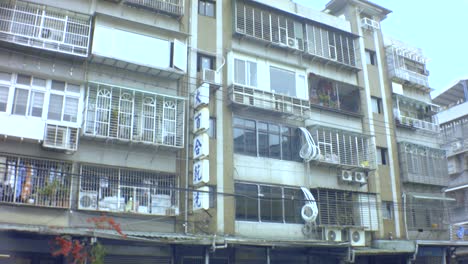 Taipei,-Taiwan---28.-Januar-2019:-Horizontale-Ansicht-Des-Alten,-Schmutzigen-Asiatischen-Wohngebäudes-Im-Ghetto-Mit-Werbetafeln,-Schildern-Einer-Chinesischen-Klinik-Und-Lily-Dry-Wash-Und-Einem-Balkon-Mit-Entblößten-Fenstern