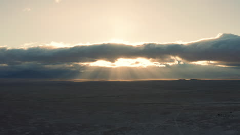 Beautiful-god-ray-sunbeams-through-clouds-over-vast-desert-at-sunrise