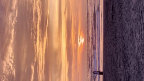 Romantischer-Orangefarbener-Sonnenuntergang-Am-Strand-Mit-Jungem-Paar,-Das-Sich-Umarmt