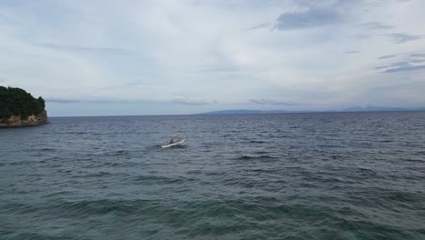 Aerial-Drone-shot-Descends-to-reveal-Filipino-Fisherman-riding-Bangka-Boat-into-the-horizon,-Catanduanes-Philippines
