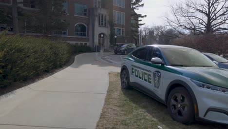 Union-building-on-the-campus-of-Michigan-State-University,-site-of-a-mass-shooting-in-February-of-2023-with-MSU-police-car-and-gimbal-video-walking-forward