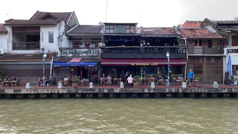 Tourists-enjoy-the-relaxing-atmosphere-of-the-riverside-cafe,-a-famous-tourist-spot-in-Malacca,-Malaysia
