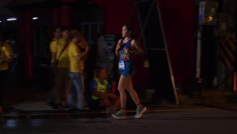 Atleta-Femenina-Corriendo-Y-Tomando-Un-Descanso-De-Agua-Durante-La-Carrera-De-Samui,-Isla-De-Koh-Samui,-Tailandia