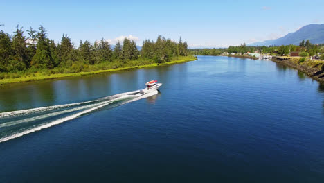 Barco-De-Motor-Navegando-Rápido-A-Lo-Largo-Del-Río-Fluvial-En-Un-Hermoso-Día-De-Verano-En-La-Región-De-Port-Alberni,-Columbia-Británica,-Canadá,-Vista-De-Seguimiento-Aéreo