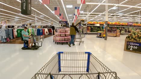 Pushing-an-empty-grocery-cart-down-the-aisle-between-fresh-produce-and-clothing