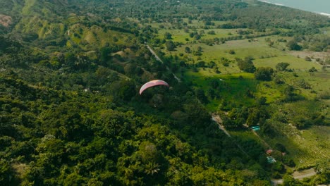 Aerial-view-chasing-a-paraglider-through-the-mountains-and-sea,-Colombia