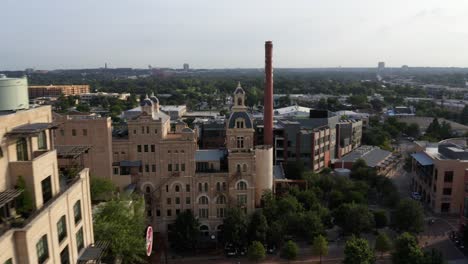 San-Antonio-Pearl-District-aerial-view-of-park-and-tower,-orbit-and-pan-right-showing-historic-warehouse-buildings-in-the-morning-with-4k-drone