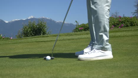 Golfspieler-Beim-Putten-Auf-Dem-Grün-Mit-Bergen-Im-Hintergrund