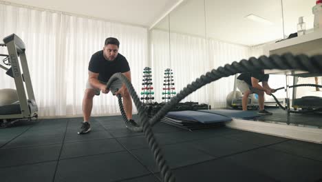 Young-man-Using-Battle-Ropes-For-fast-pacing-Whipping-Exercise-in-a-Gym