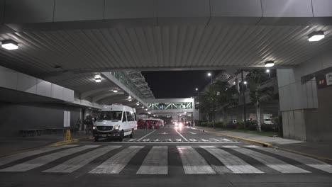 Terminal-loading-and-offloading-at-the-main-airport-with-shuttle-vans-and-bridges-overhead,-Wide-stable-shot