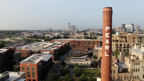 San-Antonio-Pearl-District-aerial-orbit-of-brick-pearl-tower,-pan-right-showing-historic-warehouse-district-buildings-in-4k