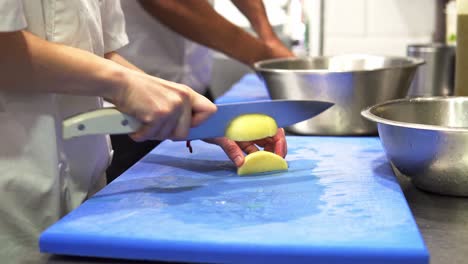 Hand-held-shot-of-chefs-cutting-up-and-preparing-large-potatoes-to-cook