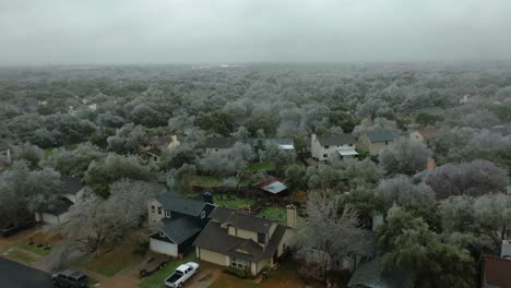 Frozen-icy-trees-in-Austin-Texas-suburban-neighborhood-during-cold-winter-freeze,-aerial-drone-flyover-South-Austin-homes-in-4k