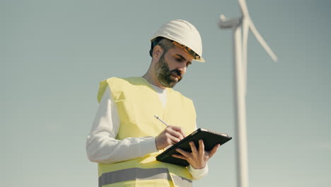 A-professional-engineer-in-a-white-helmet-checks-the-operation-of-wind-turbines-on-a-sunny-day,-symbolizing-our-commitment-to-sustainable-energy