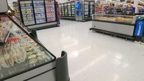 Empujando-Un-Carrito-De-Supermercado-Más-Allá-De-Las-Exhibiciones-Refrigeradas-De-Carne-En-Una-Tienda-De-Comestibles-Americana