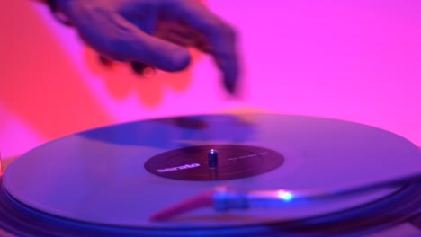 Spinning-and-scratching-motion-performed-by-hand-on-vinyl-turntable-during-live-performance,-filmed-as-close-up-on-hand-and-vinyl-deck