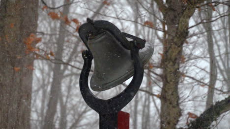 Slow-motion-snowfall-on-snowy-winter-day-with-outdoor-bell-in-background