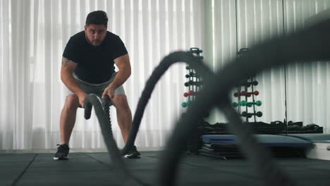 Man-Using-Battle-Ropes-For-Whipping-Exercise-in-a-Gym