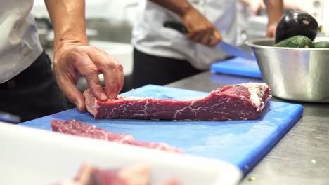 Hand-held-shot-of-chefs-cutting-up-fresh-raw-meat-on-chopping-boards