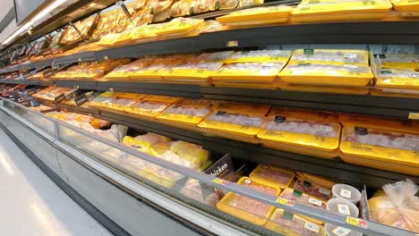 Empujando-Un-Carrito-De-Supermercado-Más-Allá-De-Las-Exhibiciones-Refrigeradas-De-Carne-En-Una-Tienda-De-Comestibles-Americana