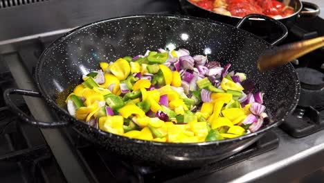 Hand-held-shot-of-a-chef-stirring-up-the-freshly-cut-vegetables-in-a-metal-pan