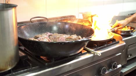 Close-up-of-a-person-cooking-in-a-frying-pan-as-a-large-flame-comes-out-on-the-stove